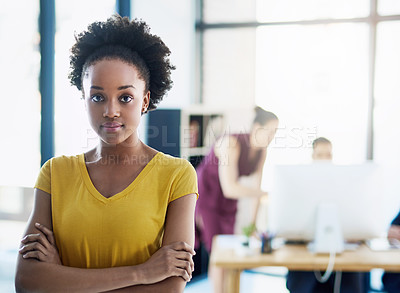 Buy stock photo Cropped portrait of an attractive young businesswoman standing with her arms folded in the office with colleagues in the background