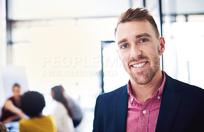 Buy stock photo Cropped portrait of a handsome young businessman standing in his office with colleagues in the background