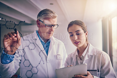 Buy stock photo Shot of two focused scientists working together solving equations on a glass wall in a laboratory