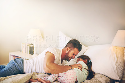 Buy stock photo Shot of a cheerful father and daughter having a tickle fight on the bed at home