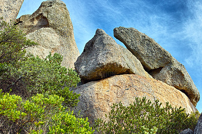 Buy stock photo Low angle of rocks and boulders with a blue sky and lush green trees growing along hiking and trekking trails of Table Mountain National Park in Cape Town, South Africa. Immersing in mother nature