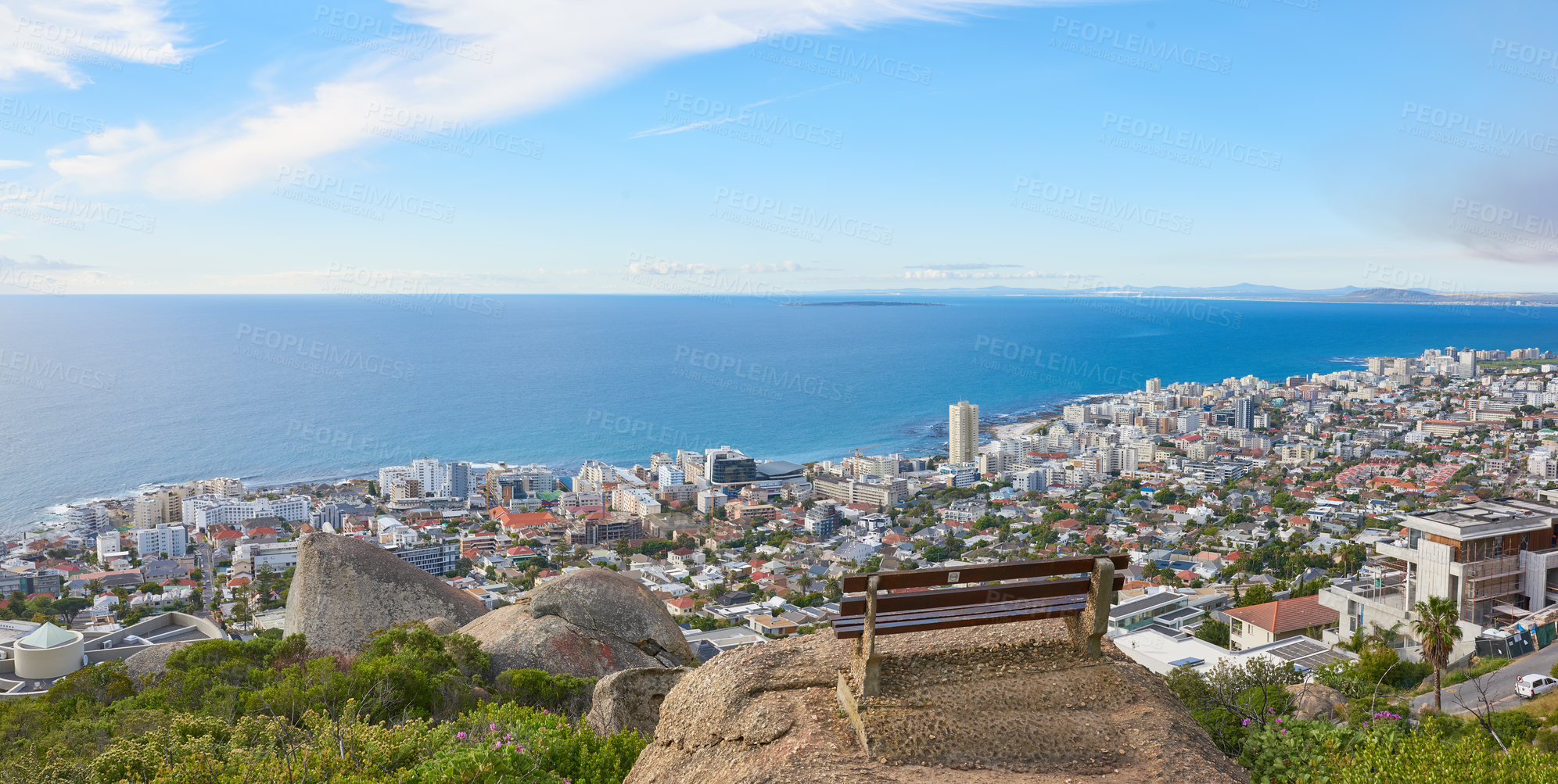 Buy stock photo Beautiful aerial landscape of an ocean in Sea Point, Cape Town, South Africa. A calm summer day with a park bench overlooking hotels and a suburban housing area in a beautiful blue seascape  