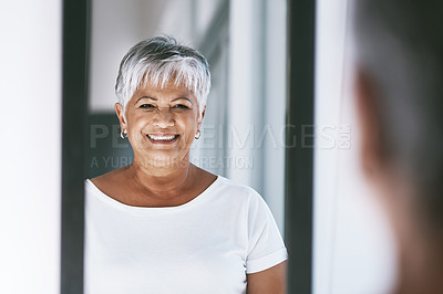 Buy stock photo Shot of a cheerful mature woman looking at her reflection in a mirror at home