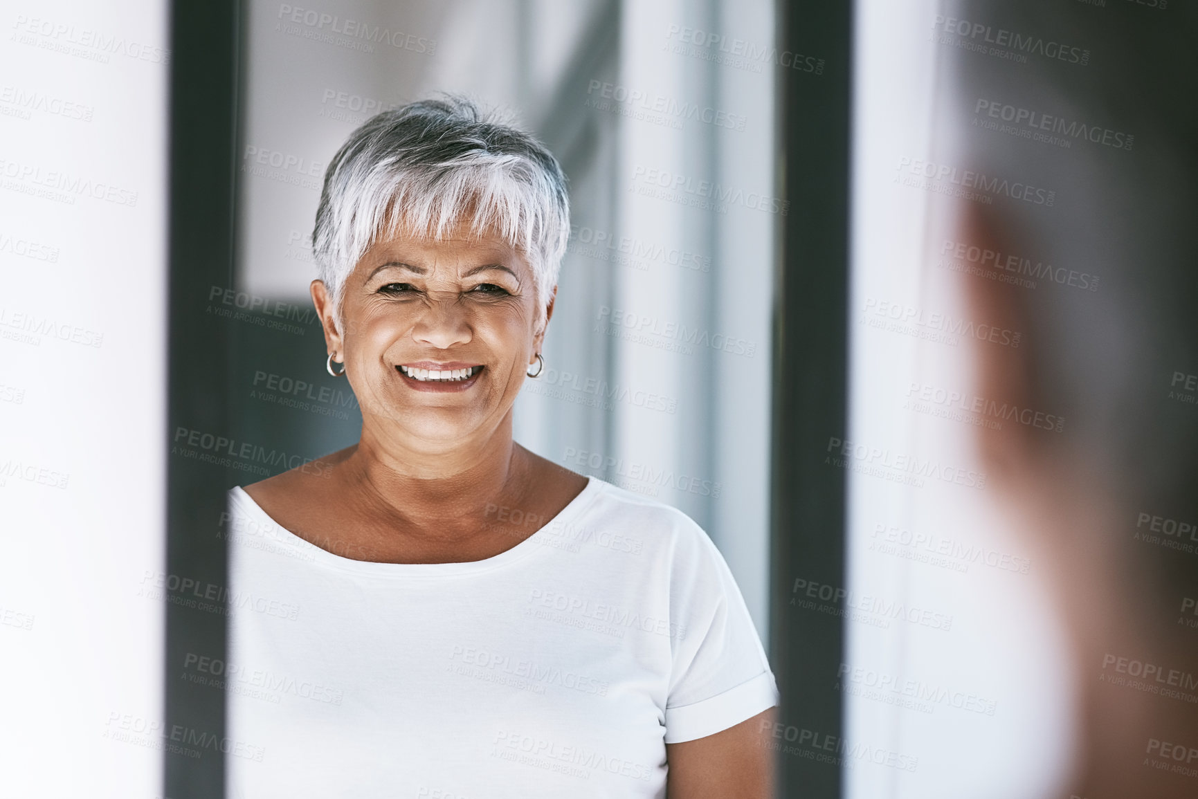Buy stock photo Shot of a cheerful mature woman looking at her reflection in a mirror at home