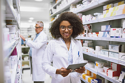 Buy stock photo Portrait of a cheerful young female pharmacist holding a digital tablet while looking at the camera in a pharmacy