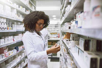 Buy stock photo Shot of a focused young female pharmacist walking around and doing stock inside of a pharmacy
