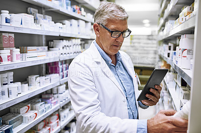 Buy stock photo Shot of a focused mature male pharmacist making notes of the medication stock on the shelves in a pharmacy