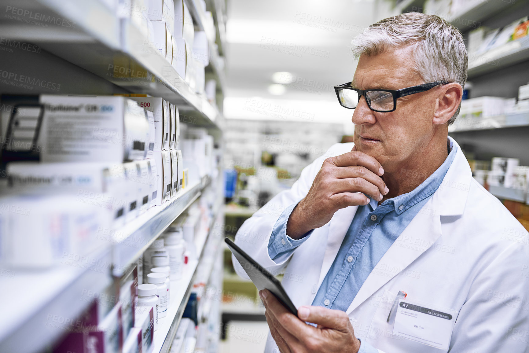 Buy stock photo Shot of a focused mature male pharmacist making notes of the medication stock on the shelves in a pharmacy