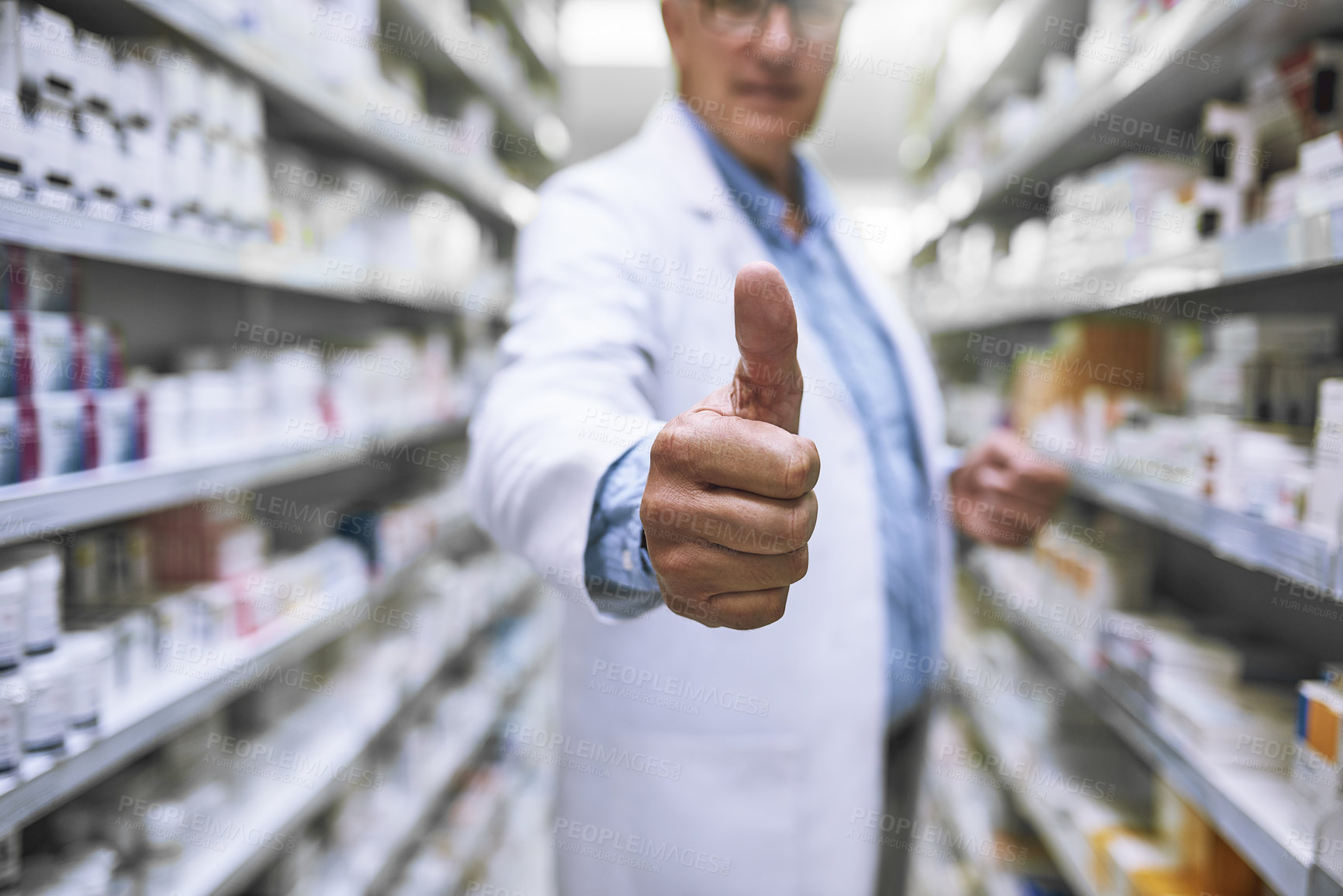 Buy stock photo Shot of a unrecognizable mature male pharmacist showing thumbs of to the camera with a closeup on his hand