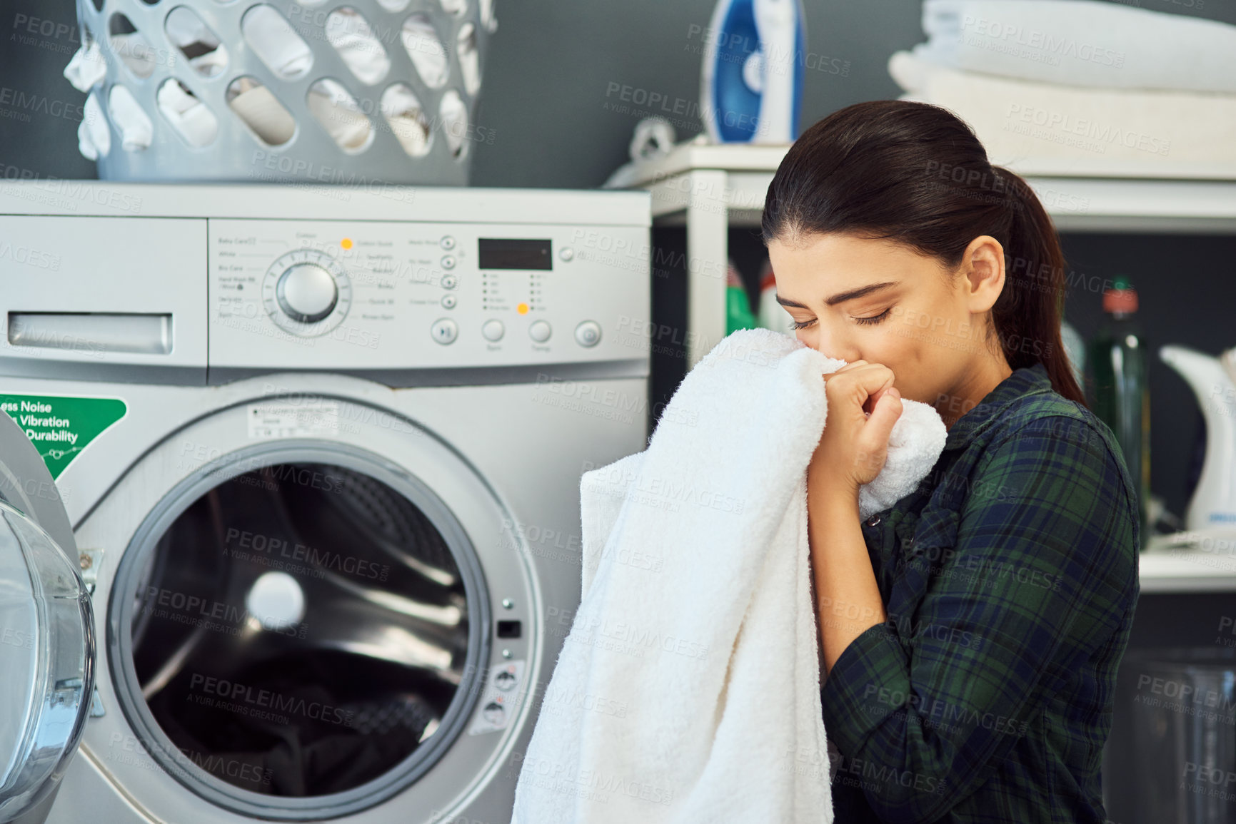 Buy stock photo Cropped shot of an attractive young woman smelling a freshly washed towel while doing laundry at home