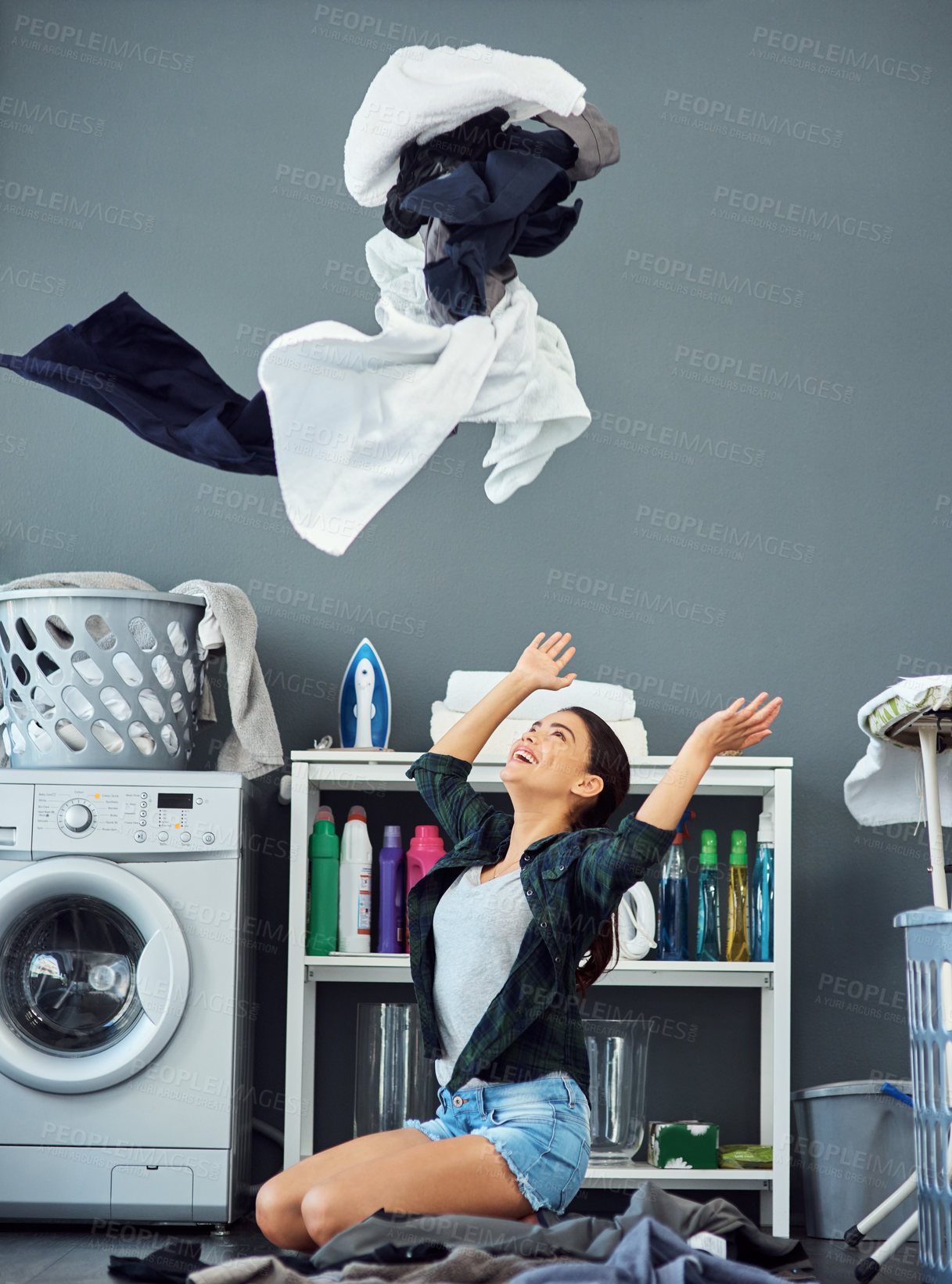 Buy stock photo Full length shot of an attractive young woman throwing her washing in the air while doing laundry at home