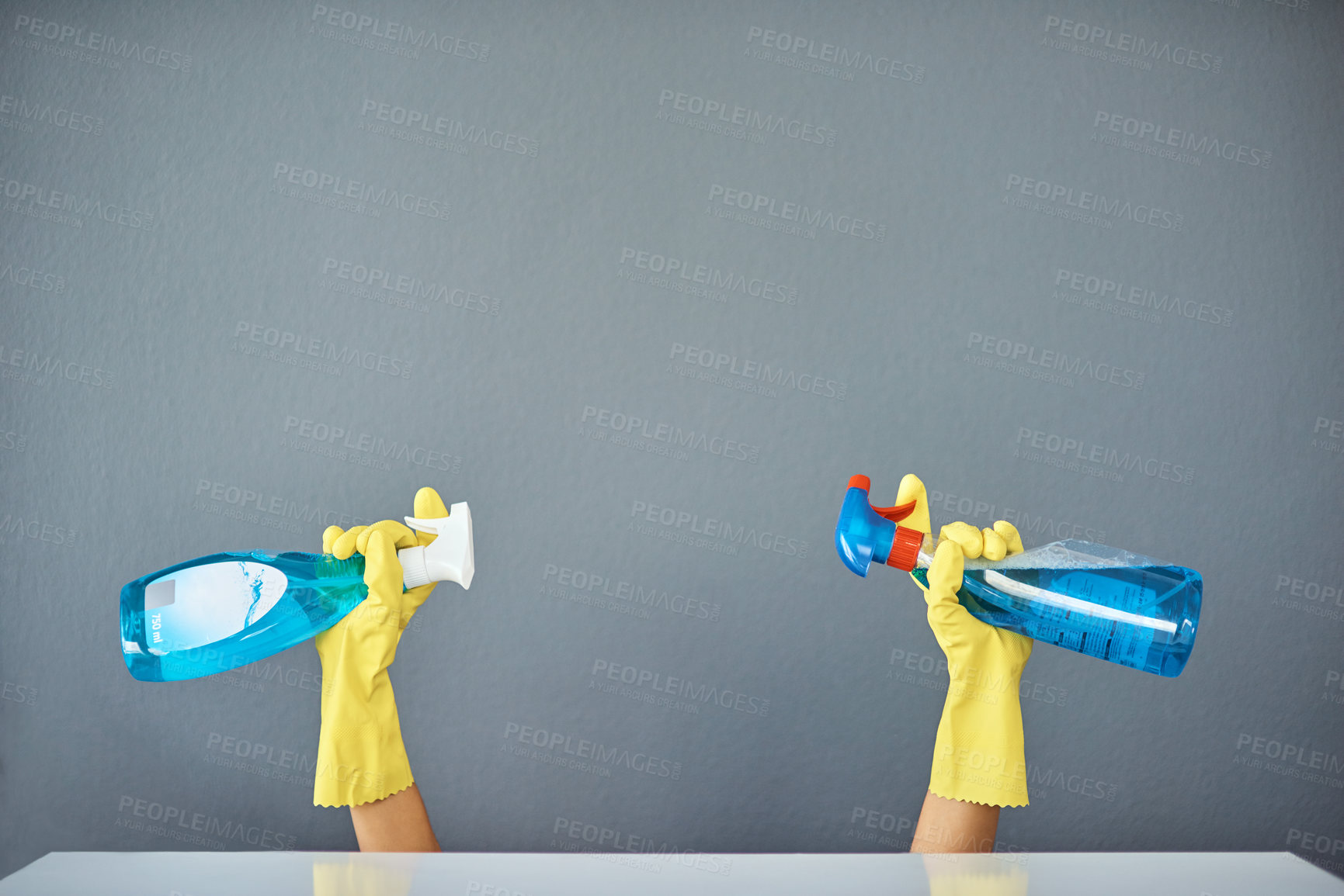 Buy stock photo Studio shot of an unrecognizable woman's holding cleaning products while wearing rubber gloves