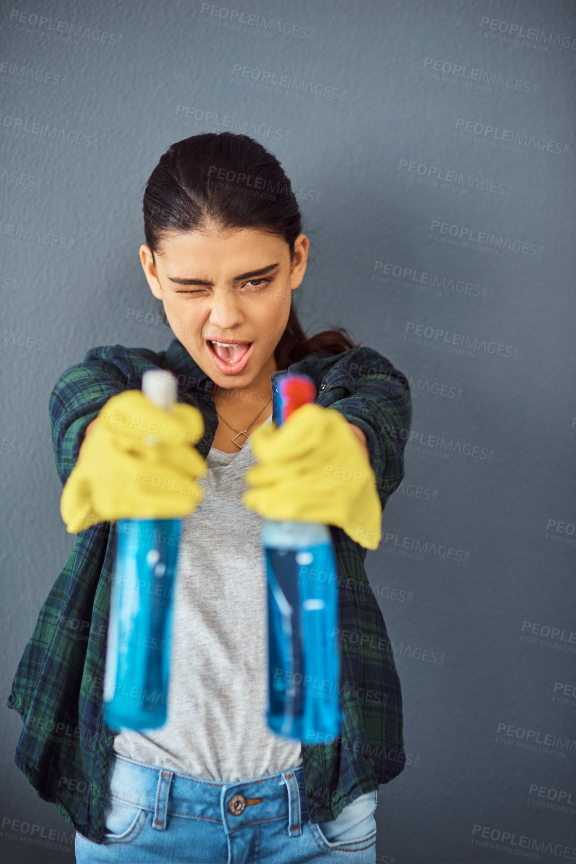 Buy stock photo Studio portrait of an attractive young woman taking aim with two spray bottles of disinfectant