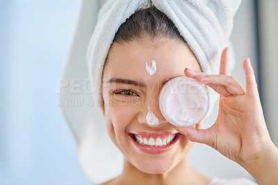 Buy stock photo Cropped portrait of a beautiful young woman applying moisturizer to her skin in the bathroom at home