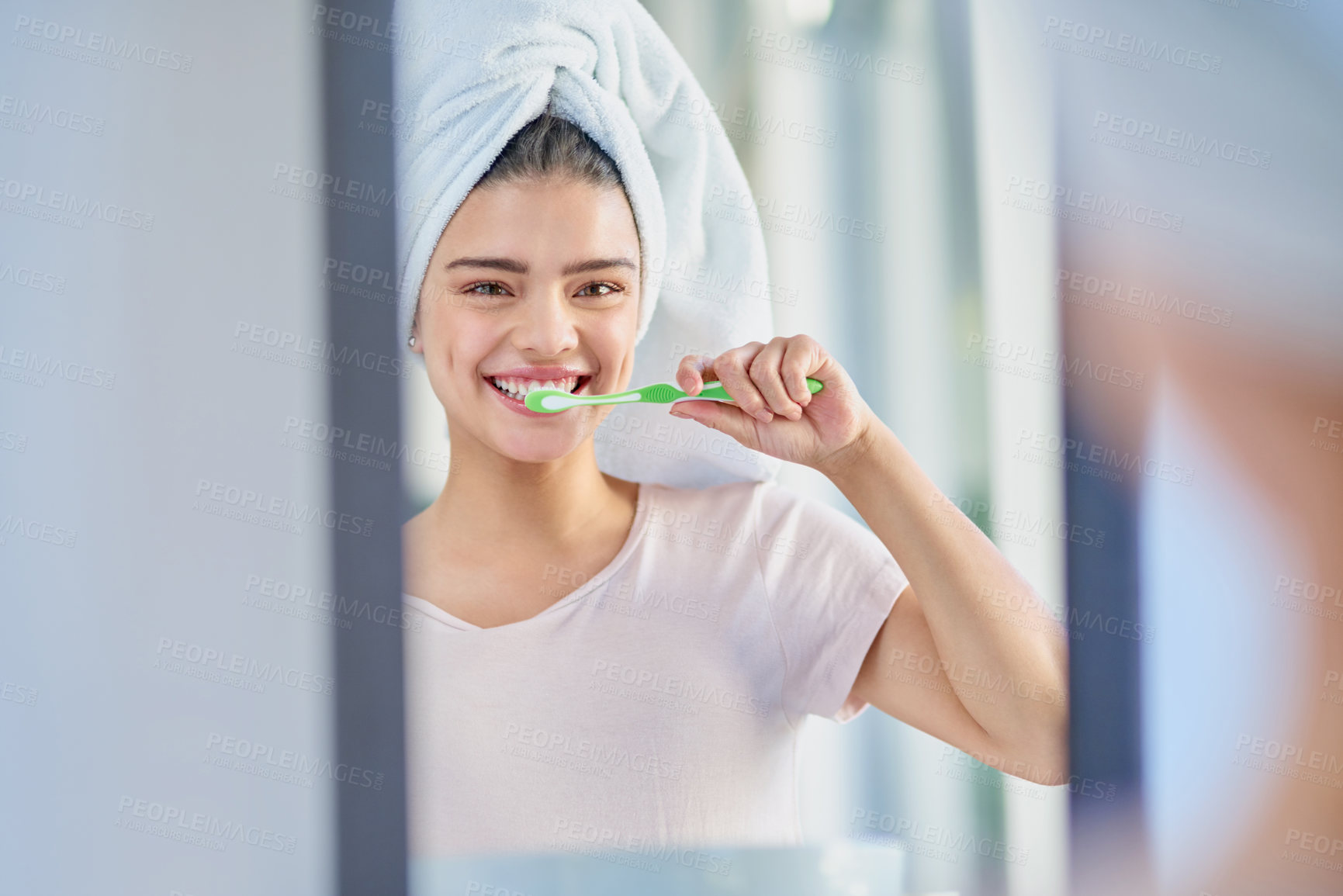 Buy stock photo Cropped portrait of a beautiful young woman brushing her teeth in the bathroom at home