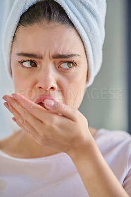 Buy stock photo Cropped shot of a beautiful young woman checking her breath herself at home