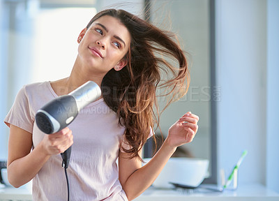 Buy stock photo Cropped shot of a beautiful young woman blowdrying her hair in the bathroom at home