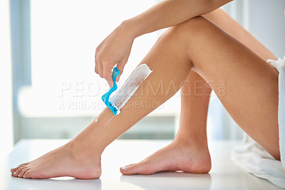 Buy stock photo Cropped shot of an unrecognizable woman shaving her legs in the bathroom at home