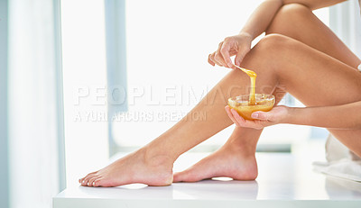 Buy stock photo Cropped shot of an unrecognizable woman applying wax to her legs in the bathroom at home