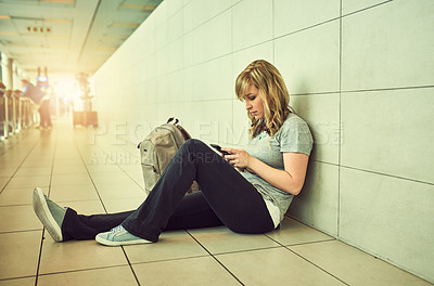 Buy stock photo Shot of a young woman sitting on the floor in an airport