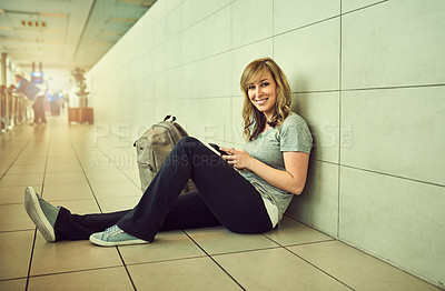 Buy stock photo Shot of a young woman sitting on the floor in an airport