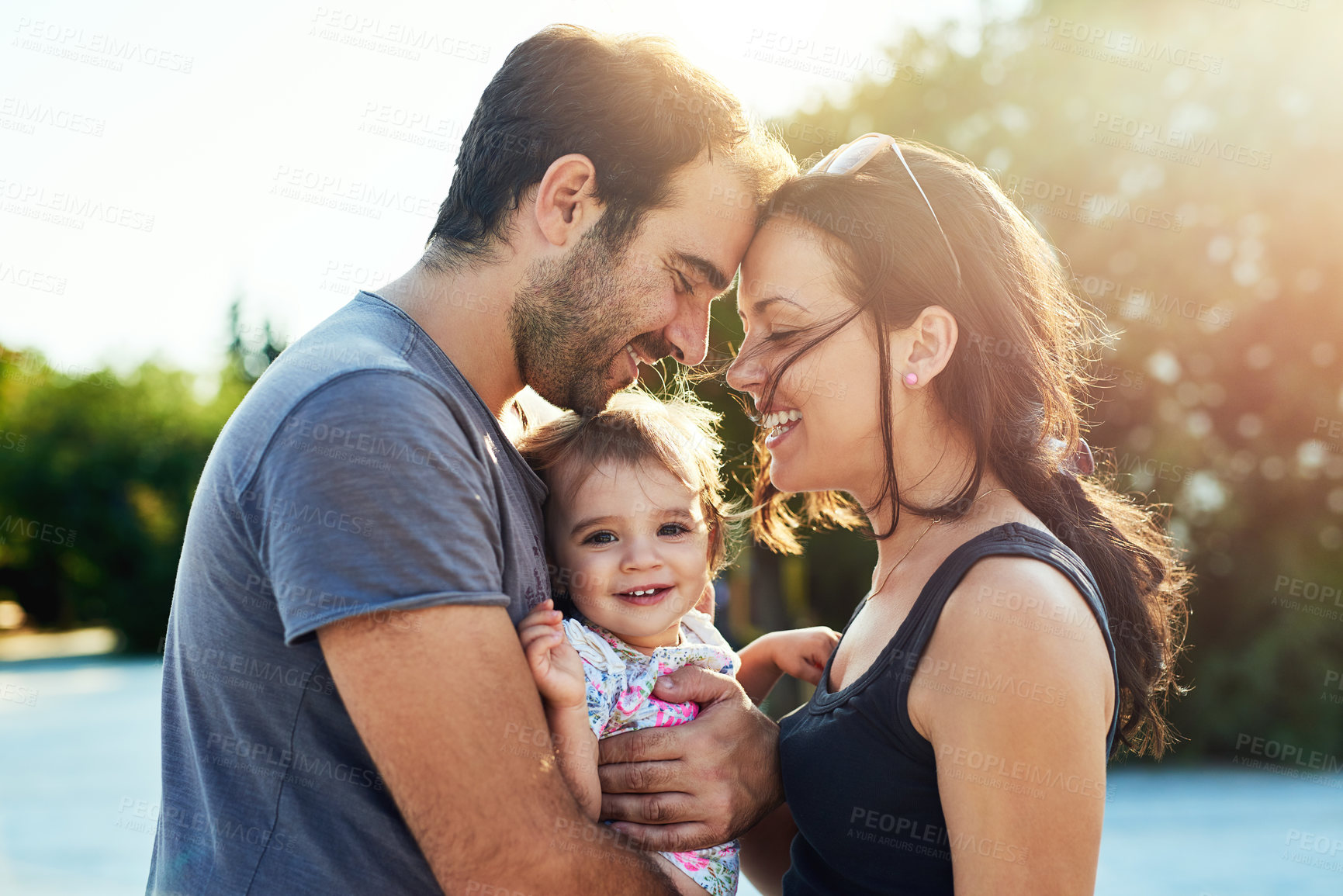 Buy stock photo Happy, love and parents with baby in park for bonding, loving relationship and relax together outdoors. Family, sunshine and mom, dad and child for embrace, affection and forehead touch on weekend