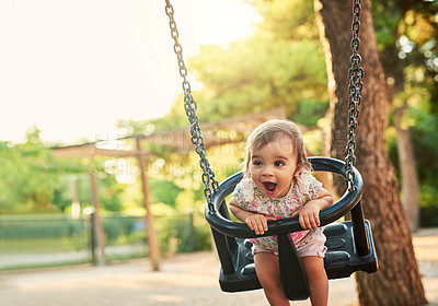 Buy stock photo Shot of little girl playing on a swing in a park