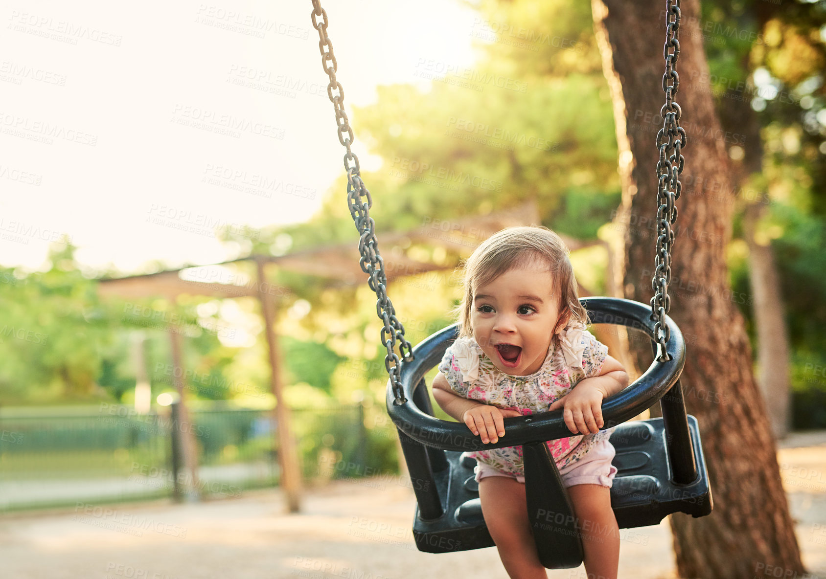 Buy stock photo Shot of little girl playing on a swing in a park