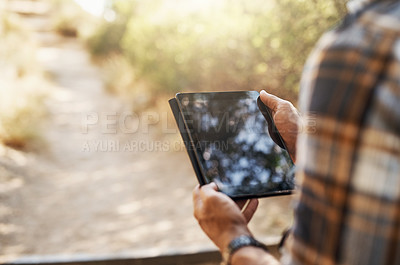 Buy stock photo Cropped shot of an unrecognizable man using his tablet while hiking in the mountains