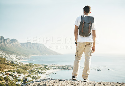 Buy stock photo Rearview shot of an unrecognizable young man taking in the views while hiking in the mountains