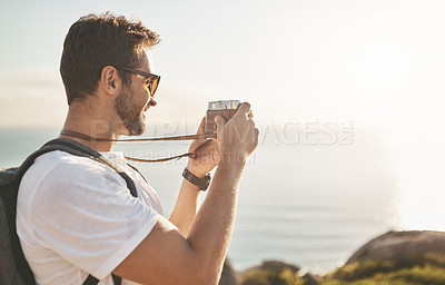 Buy stock photo Cropped shot of a handsome young man taking photographs while hiking in the mountains