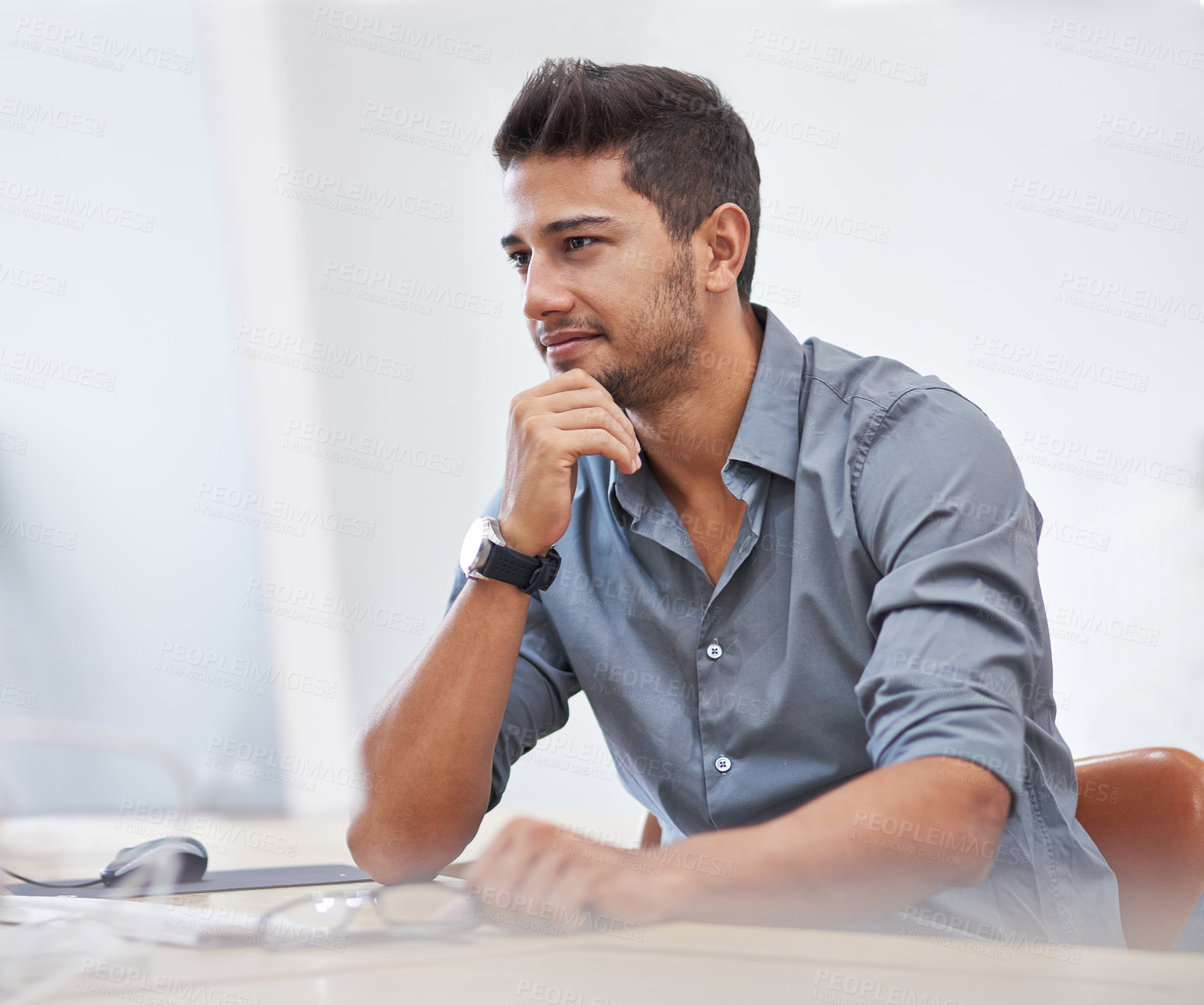 Buy stock photo Shot of a confident young man working on his computer in the office during the day