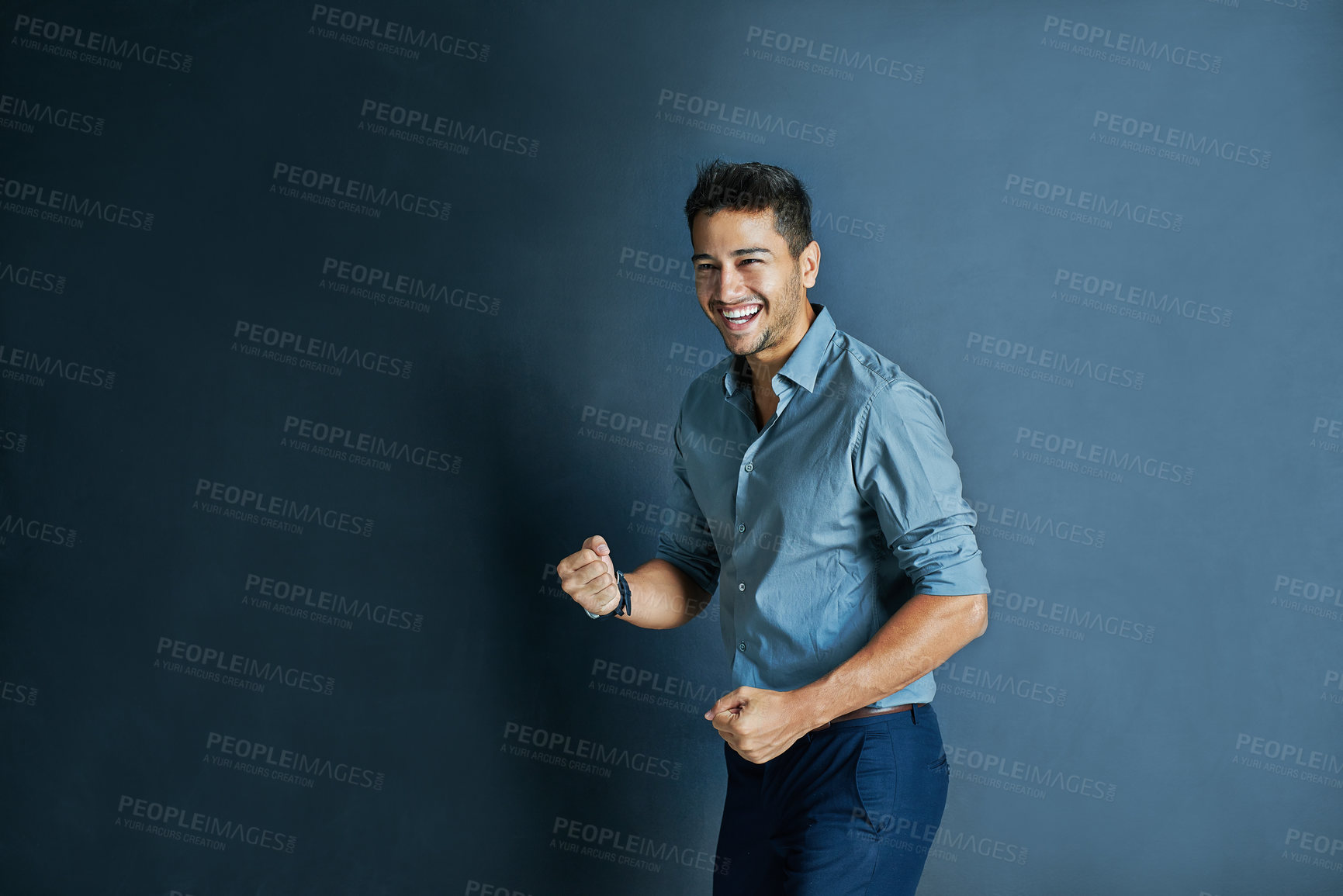 Buy stock photo Celebration, fist pump and portrait of a businessman in a studio with achievement or winning. Happy, smile and professional male employee winner with success to celebrate isolated by blue background.