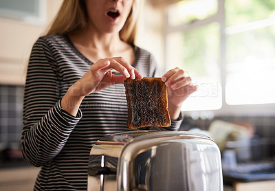 Buy stock photo Shot of a woman removing a slice of burnt toast from a toaster at home