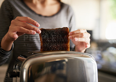 Buy stock photo Cropped shot of a woman removing a slice of burnt toast from a toaster at home