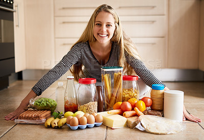 Buy stock photo Shot of an attractive young woman surrounded by various food in the kitchen at home