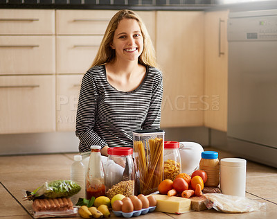 Buy stock photo Shot of an attractive young woman surrounded by various food in the kitchen at home
