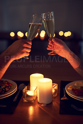 Buy stock photo Cropped shot of an unrecognizable couple having a celebratory toast over a candle lit dinner at night