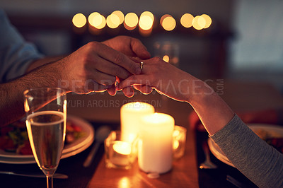 Buy stock photo Shot of an unrecognizable man proposing to his wife over a candle lit dinner at night