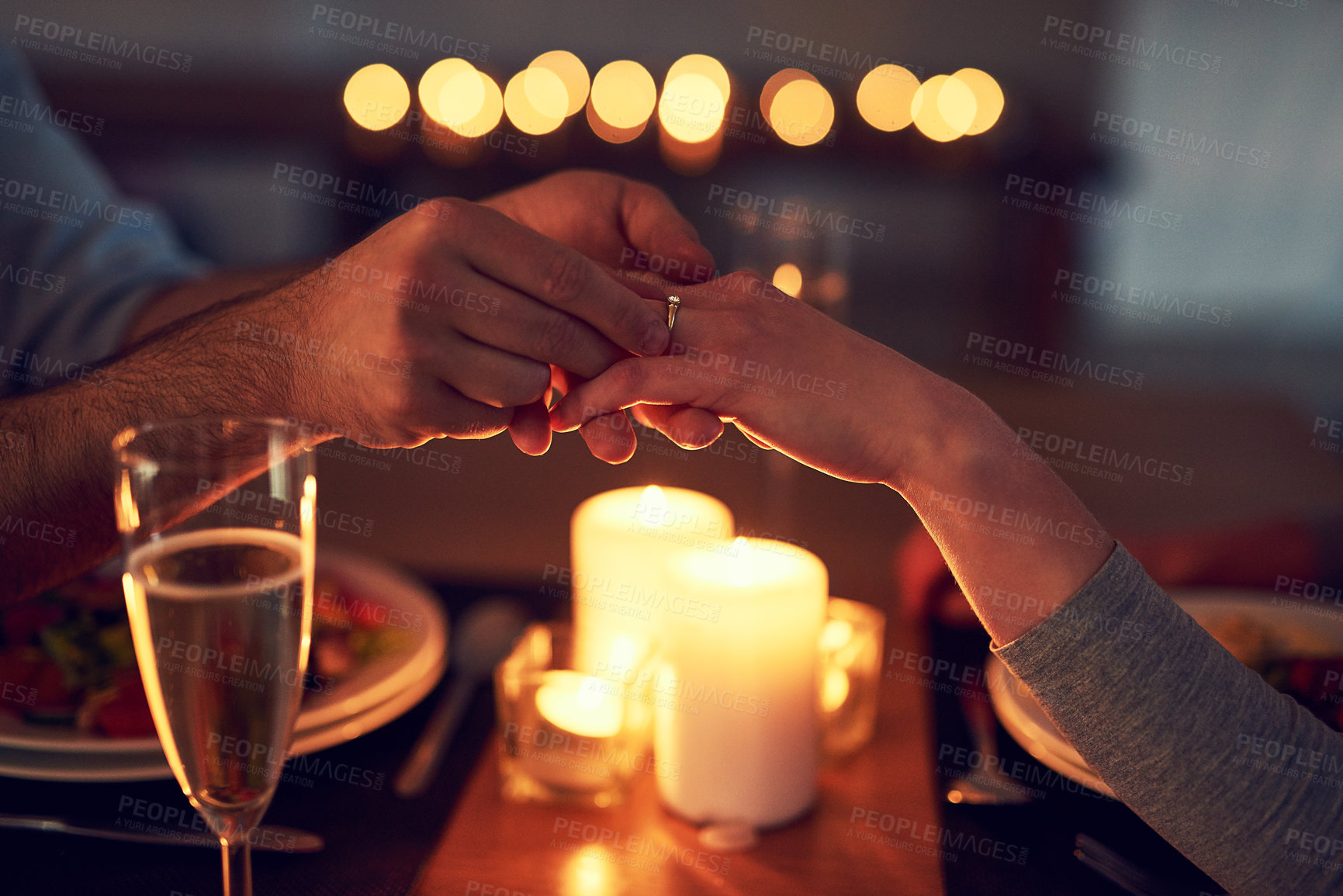 Buy stock photo Shot of an unrecognizable man proposing to his wife over a candle lit dinner at night