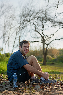 Buy stock photo Full length portrait of a handsome male athlete tying his laces while out for a hike in the forest