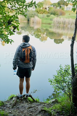 Buy stock photo Rearview shot of a young male athlete taking in the lake views while hiking in the forest