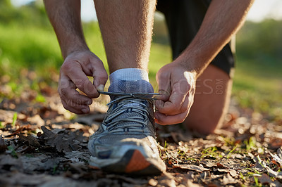 Buy stock photo Closeup shot on an unrecognizable male athlete tying his laces while out for a hike in the forest