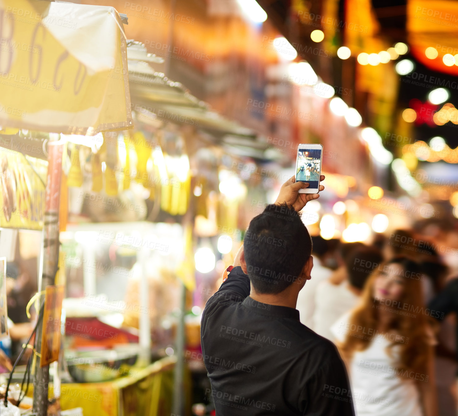 Buy stock photo Rearview shot of a young man taking pictures while touring a foreign city