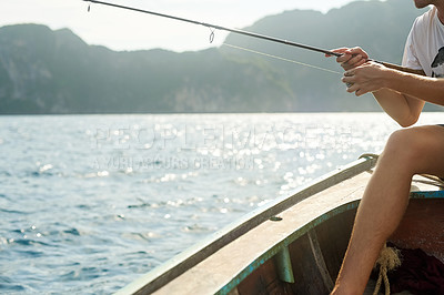 Buy stock photo Cropped shot of an unrecognizable young man fishing while out at sea on his boat