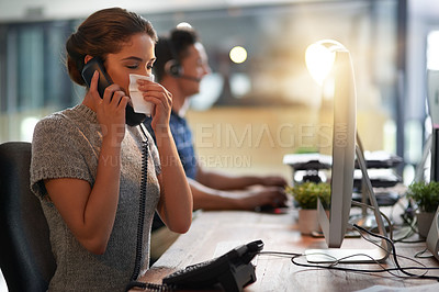 Buy stock photo Shot of a young businesswoman blowing her nose while talking on a phone in an office
