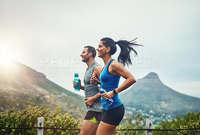 Buy stock photo Shot of a young attractive couple training for a marathon outdoors