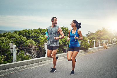 Buy stock photo Shot of a young attractive couple training for a marathon outdoors