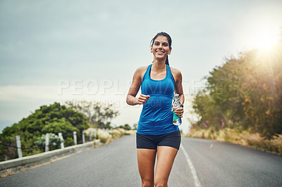 Buy stock photo Fitness, happy woman and running with water bottle for exercise, cardio or wellness on road in nature. Female athlete, smile or workout on trail for health, sport or marathon training with sportswear