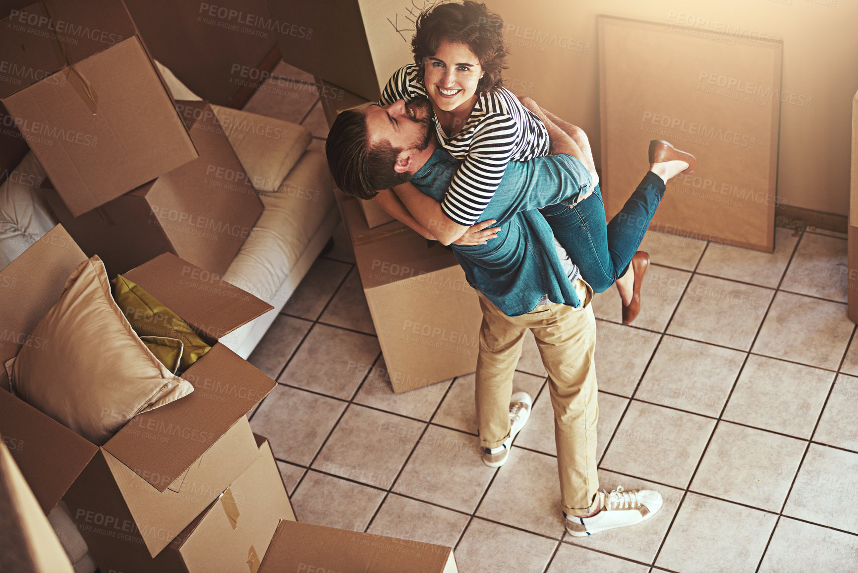 Buy stock photo Shot of a happy young couple hugging as they move into their new home